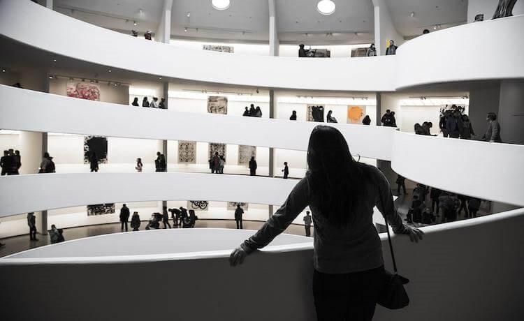 une femme observe les oeuvres dans une salle d'exposition