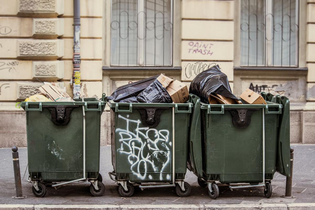 Trois bennes à ordures pleines de déchets dans une rue