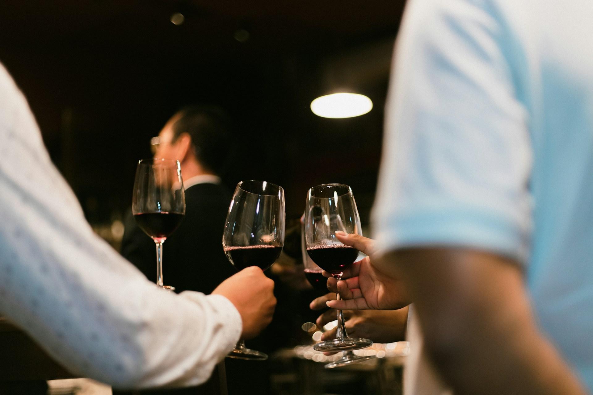 Un groupe de personnes trinquant avec des verres de vin rouge dans une ambiance chaleureuse