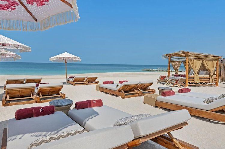 transats avec coussins sur une plage de sable blanc avec vue sur la mer