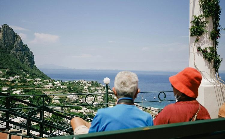 un couple de personnes âgées assis devant la mer bleu