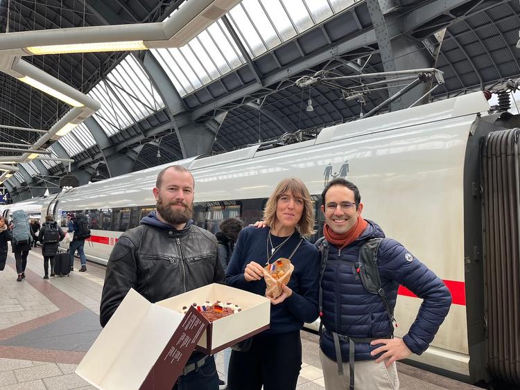 trois personnes avec des pâtisseries devant un train 