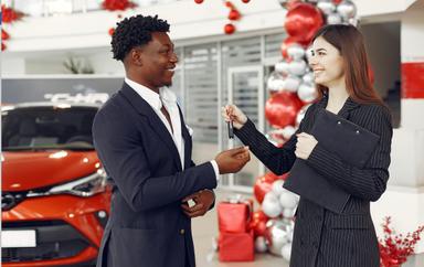 Une vendeur de voiture tendant un clef à l'acheteur.