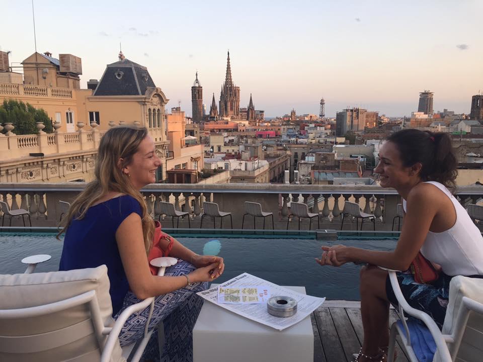 Deux amies profitant d’un moment de détente sur un rooftop de Barcelone avec une vue panoramique sur la ville