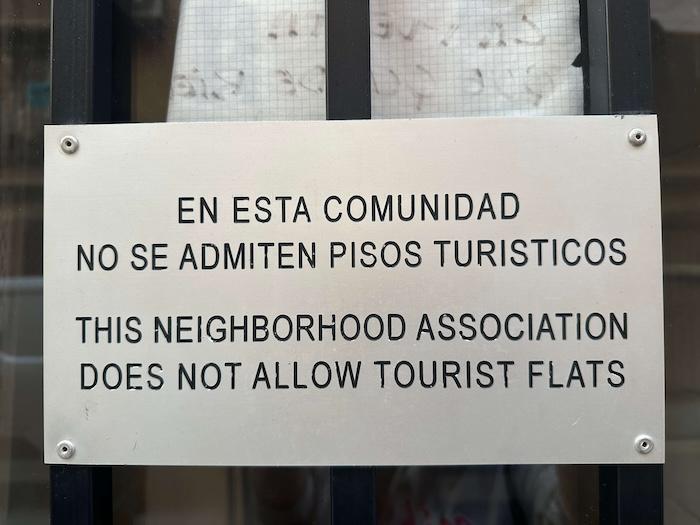 Plaque sur une porte d'immeuble "Ce quartier n'accepte pas les appartements touristiques"