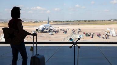 une voyageuse avec valise de dos à l'aéroport de valencia devant un avion