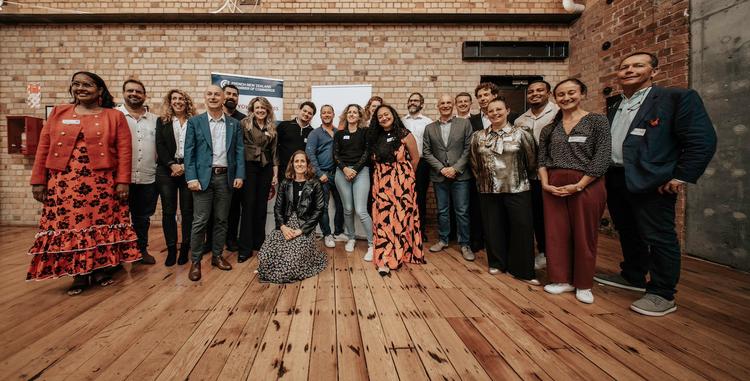 Groupe de personnes participant a la soiree French tech NZ a Auckland, posant devant un mur en briques