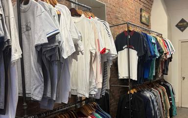 Des vêtements suspendus à un portant dans une boutique.