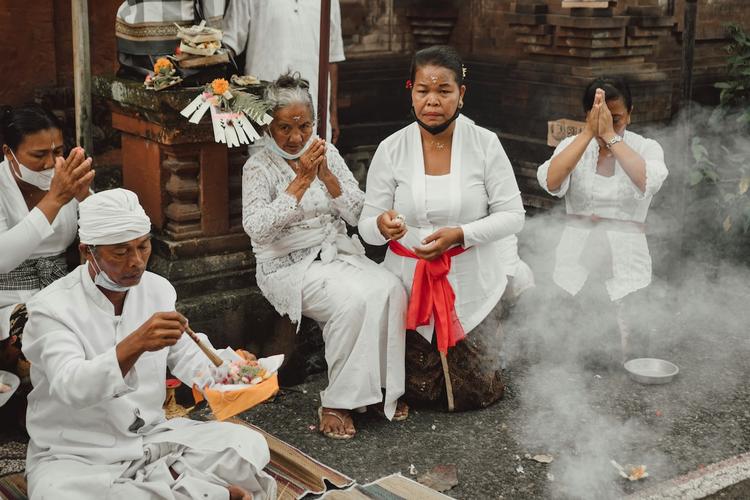 quatre balinais habillés en blanc qui prient dans un temple