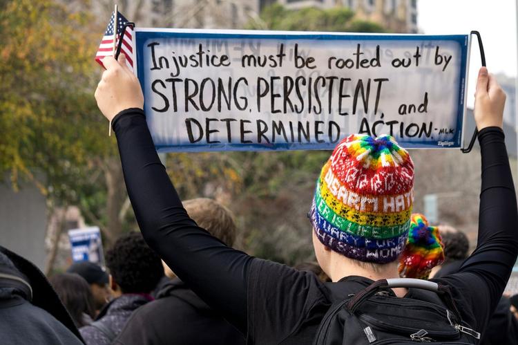 Une personne tient dans ses mains une pancarte qu'il hisse.