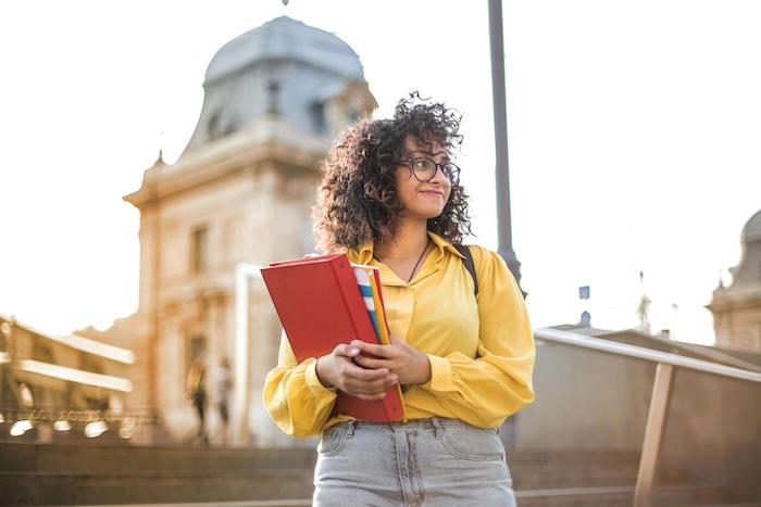 femme en veste jaune tenant un livre rouge