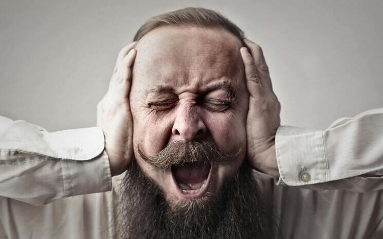 homme en colère qui se bouche les oreilles à cause du bruit