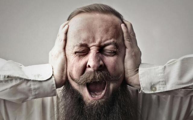 homme en colère qui se bouche les oreilles à cause du bruit