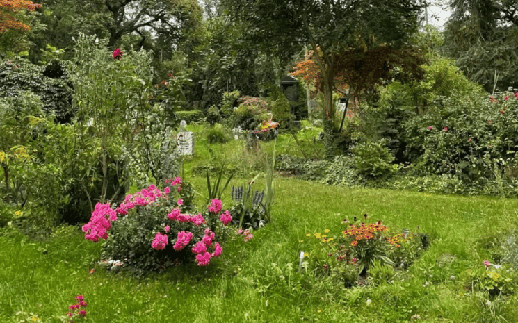 cimetière fleuris et vers avec des buissons, des arbres et des plantes également sur les tombes