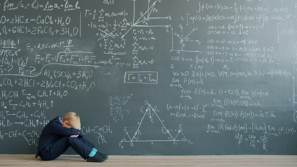 un enfant pleure devant un problème de mathématiques au tableau 