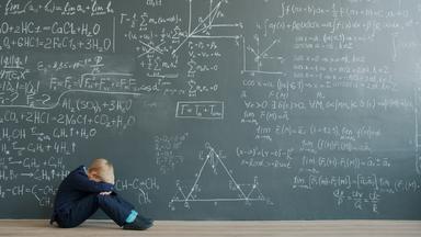 un enfant pleure devant un problème de mathématiques au tableau 