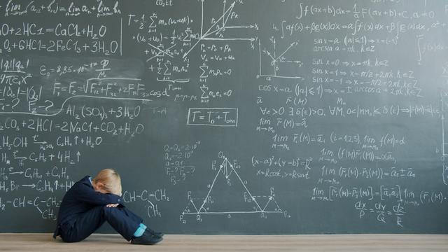un enfant pleure devant un problème de mathématiques au tableau 