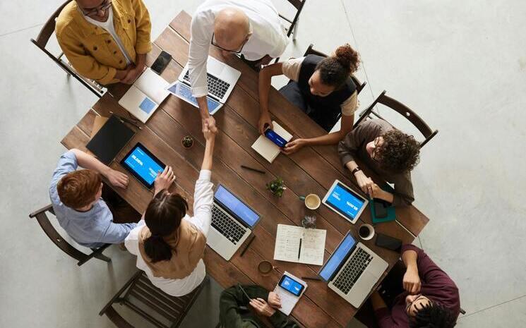 8 personnes sont autour d'une table et travaillent sur leurs ordinateurs