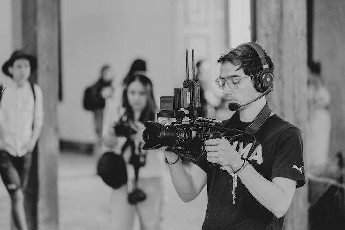 photo en noir et blanc d'un journaliste cameraman filmant en interieur avec du materiel professionnel
