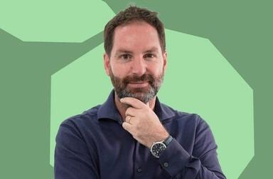 un homme se tient le menton devant un fond vert