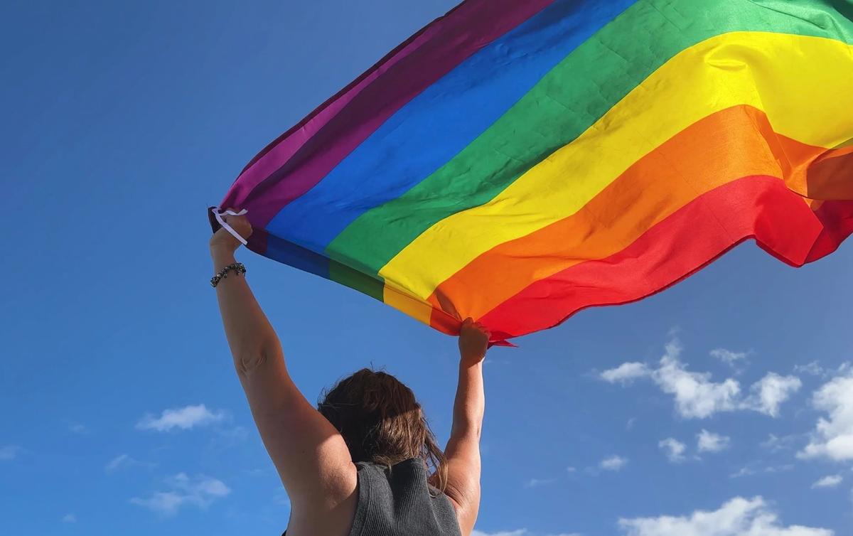 Le drapeau gay tenu a bout de bras par une personne