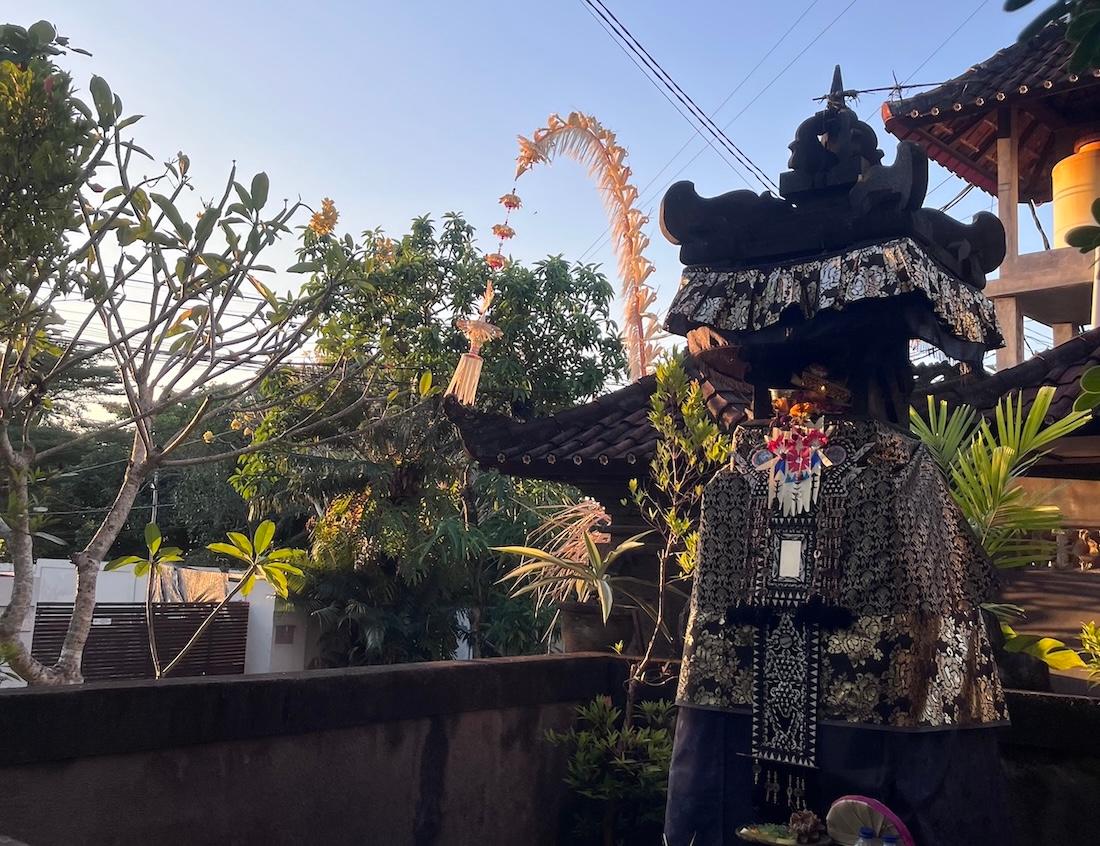 un petit temple balinais au premier plan avec un penjor, tige de bambou décorative, en arrière plan