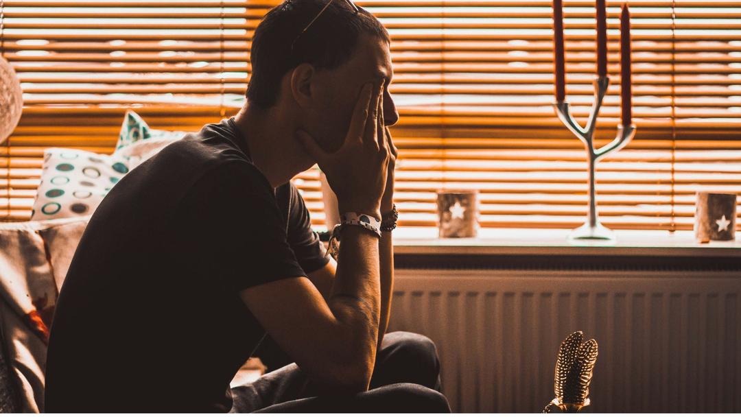 homme triste assis qui se frotte les yeux