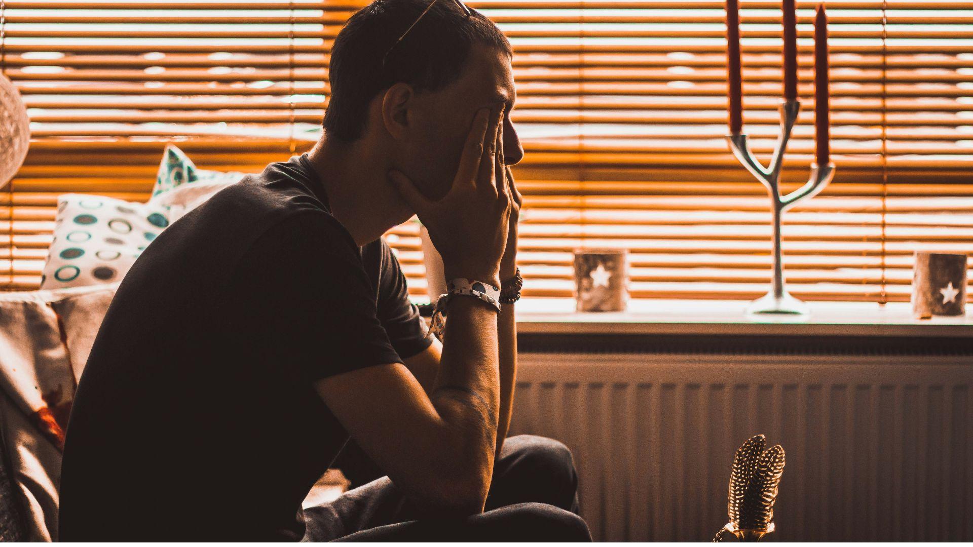 homme triste assis qui se frotte les yeux