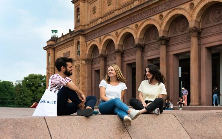 Trois personnes assises devant la Hamburger Kunsthalle.