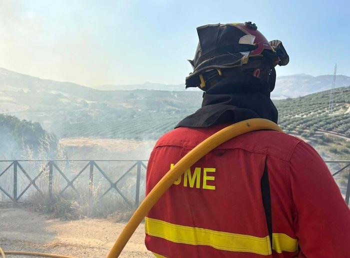 vue de dos d'un pompier espagnol de l'Unidad Militar de Emergencias habillé en rouge avec un tuyeau devant un incendie en Andalousie