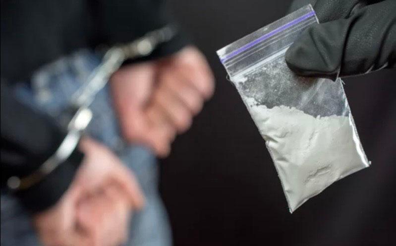 Sachet d’héroïne et mains menottées 