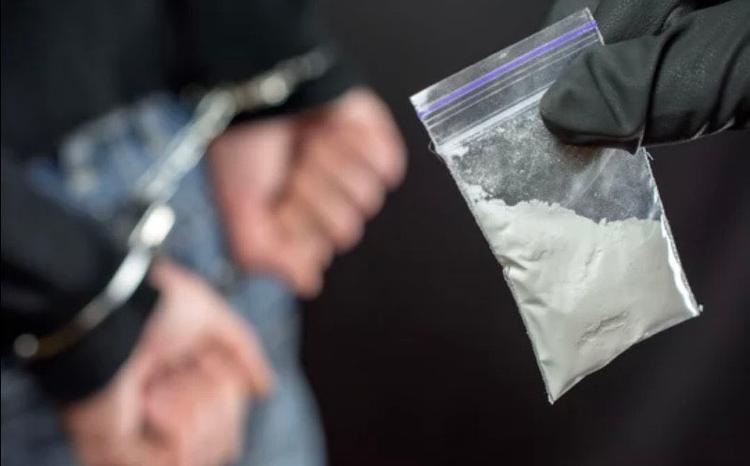 Sachet d’héroïne et mains menottées 