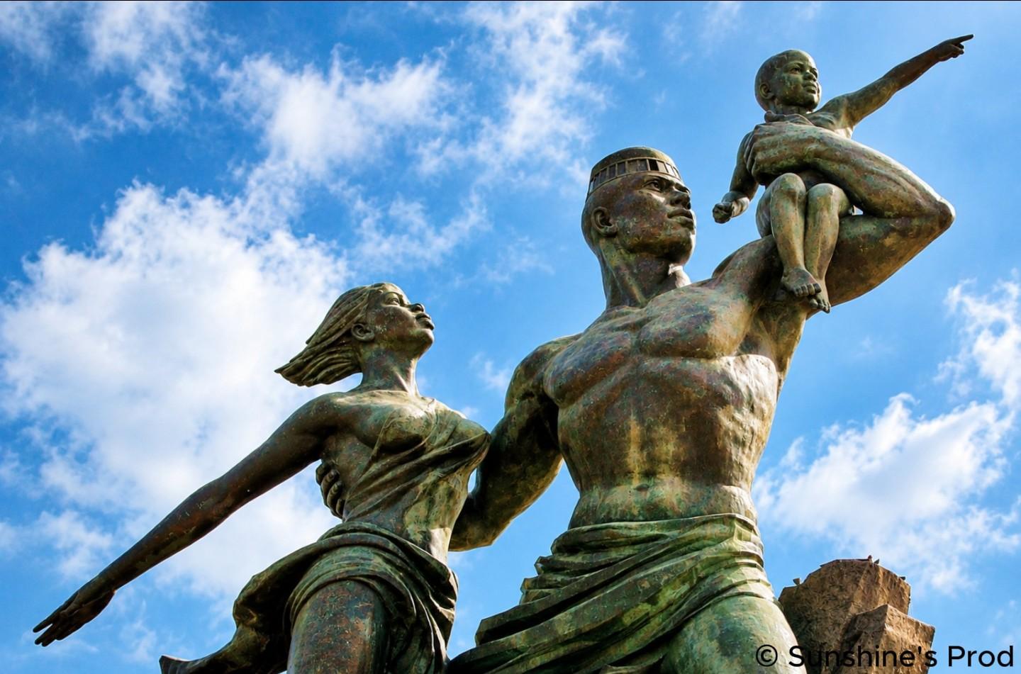 Monument de la Renaissance africaine à Dakar, représentant trois figures en bronze tournées vers l’horizon sous un ciel bleu.