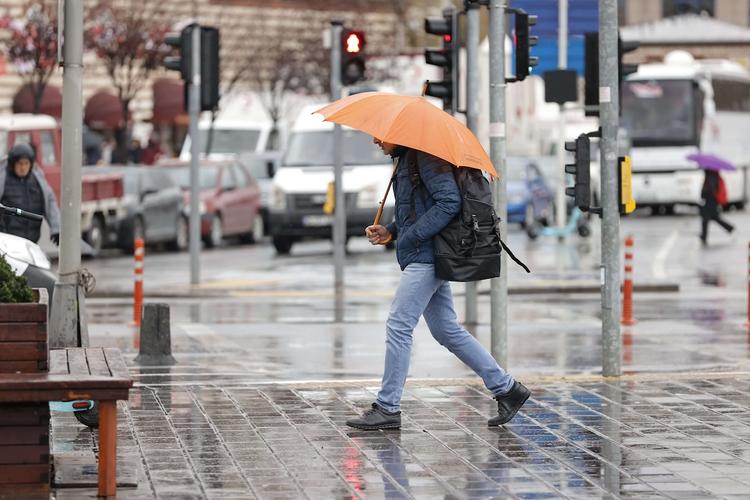personne marchant sous la pluie avec un paparpluie orange à valence