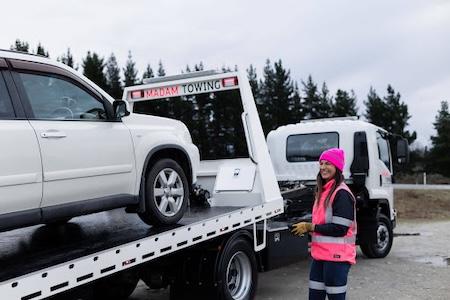 remorque de voitur avec une voiture dessus et une dame à coté