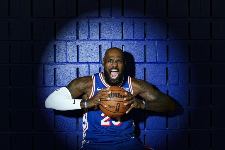 LeBron James pose en maillot des Philadelphia 76ers, ballon en main