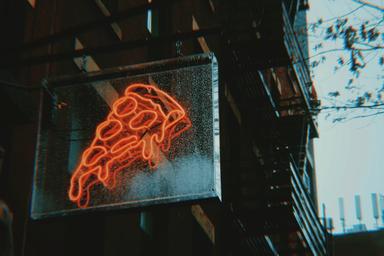 Une part de pizza typique de New York tenue à la main dans une rue animée de Manhattan