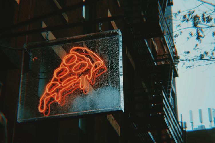 Une part de pizza typique de New York tenue à la main dans une rue animée de Manhattan