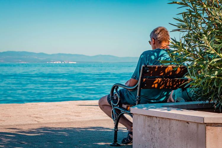 un retraité sur banc face à la mer en espagne