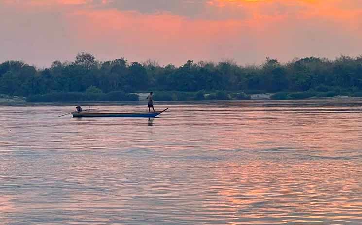 Après-midi du 10 mars 2024. Des pêcheurs sont debout sur un bateau en train de jeter leurs filets sur le Mékong. (Sovann Sreypich CamboJa News)