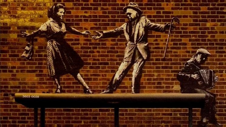 L'une des oeuvres de Banksy : On y voit deux personnes qui dansent ensemble, sur un mur de briques