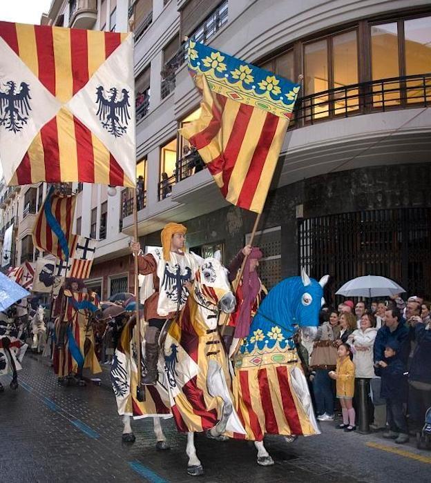 Des Valenciens en habits traditionnels en train de défiler à cheval avec un drapeau