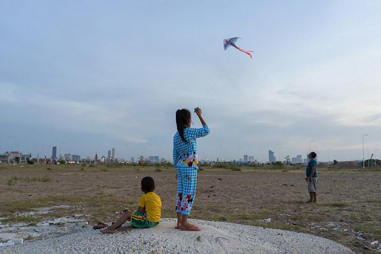 A girl plays with a kite on an area of wetland that has been filled