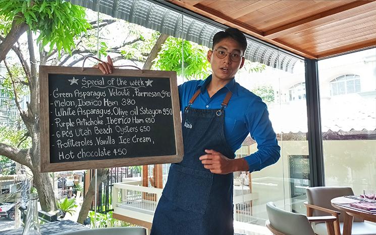 Un serveur du bistrot Alpea a Bangkok montre le menu sur l'ardoise