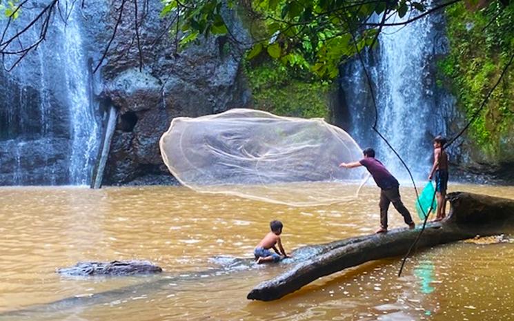 Photo de villageois Kroeung en train de pecher au filet devant une chute d'eau au Cambodge