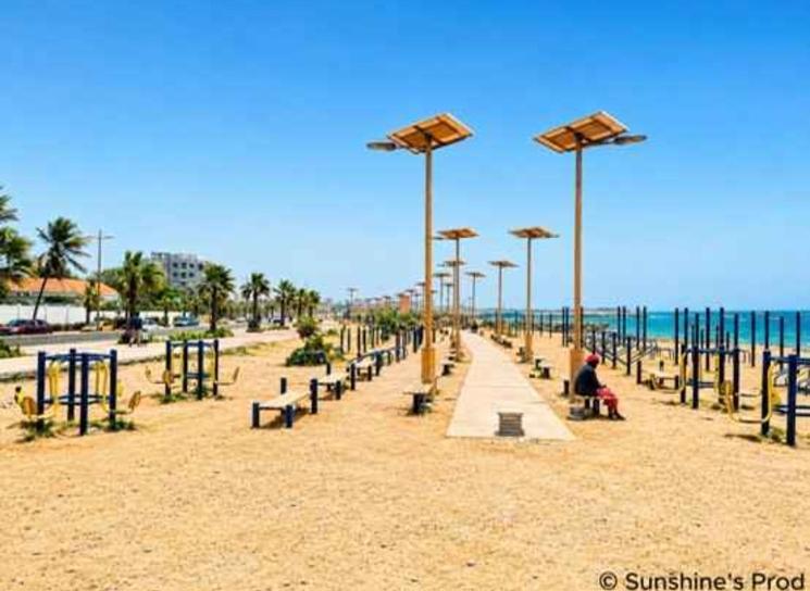 Promenade du littoral de Dakar avec équipements sportifs en plein air, bordée de palmiers et longeant l’océan Atlantique.