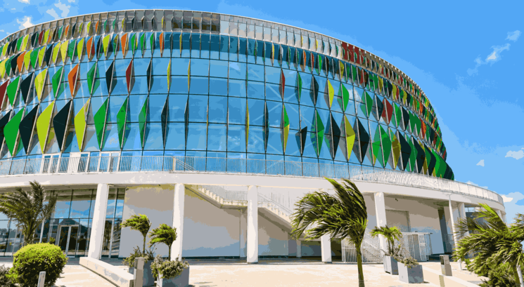 Façade moderne de la Dakar Arena à Diamniadio, près de Dakar, avec son architecture circulaire en verre et ses panneaux colorés inspirés de l’art africain. Cette salle multifonctionnelle de référence au Sénégal accueille des compétitions sportives internationales, des concerts, des salons et de grands événements culturels.