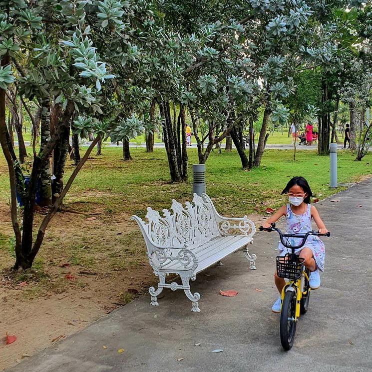 Une fillette masquee sur sa bicyclette dans le parc Benjakitti a Bangkok