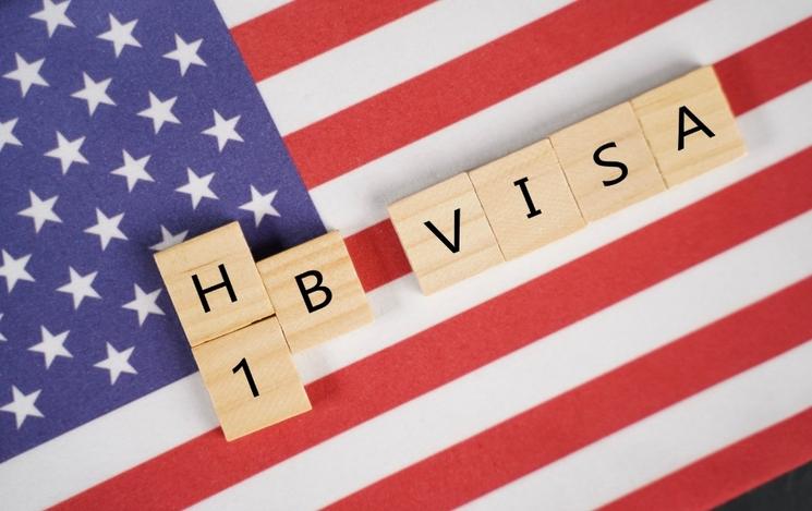 Un drapeau américain et le mot H1-B Visa en lettre de scrabble