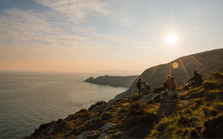 Un groupe de personnes sur une montagne avec le coucher du soleil en arrière-plan. À Howth, Irlande